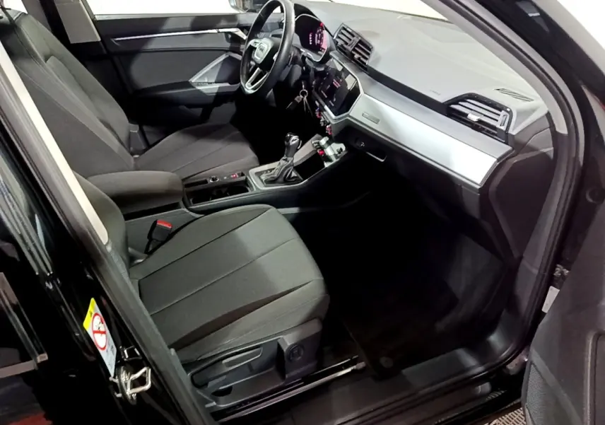 Intérieur côté conducteur de l'Audi Q3 noir 2020, avec tableau de bord moderne et volant multifonctions cuir.