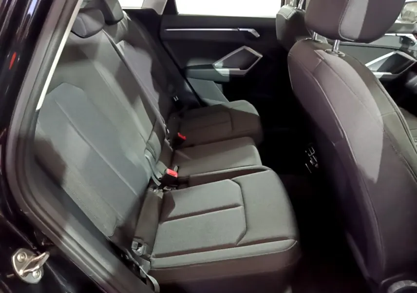 Vue intérieure montrant les sièges arrière noirs du côté gauche de l'Audi Q3 35 TDI 2020 avec garnitures tissu.