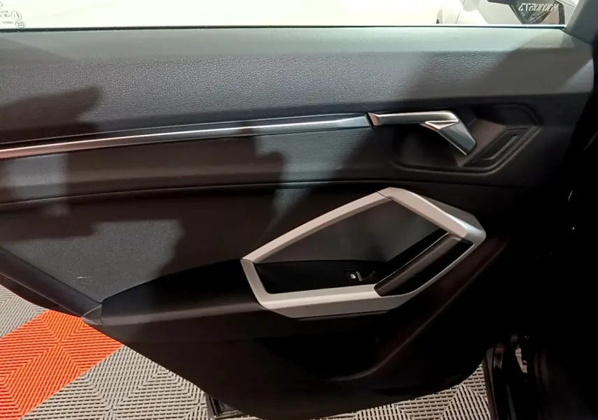 Porte intérieure côté droit noire de l'Audi Q3 35 TDI 150 S tronic Business Line 2020 avec poignée argentée.