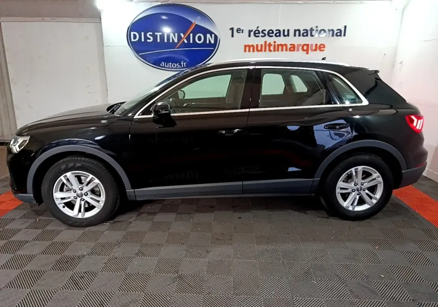 Audi Q3 noir vue de profil côté gauche, stationné en intérieur avec logo Distinxion en arrière-plan.