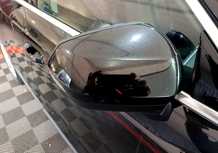 Rétroviseur extérieur côté gauche noir brillant d'un Audi Q3 35 TDI 2020 avec carrosserie noire vue en gros plan.