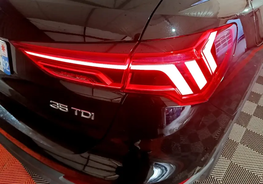 Gros plan sur le feu arrière droit rouge vif d’un Audi Q3 noir 35 TDI avec logo visible sur le coffre.