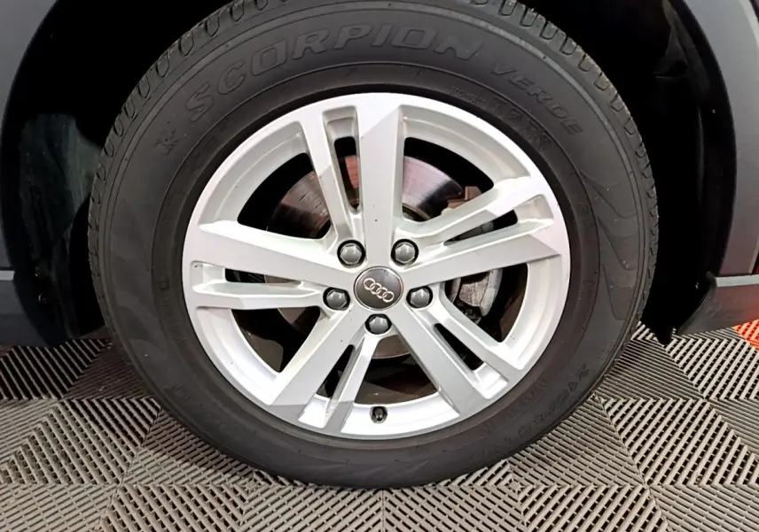 Gros plan sur la roue avant droite d’un Audi Q3 noir 35 TDI 150 S tronic avec jante argentée à 5 branches doubles.