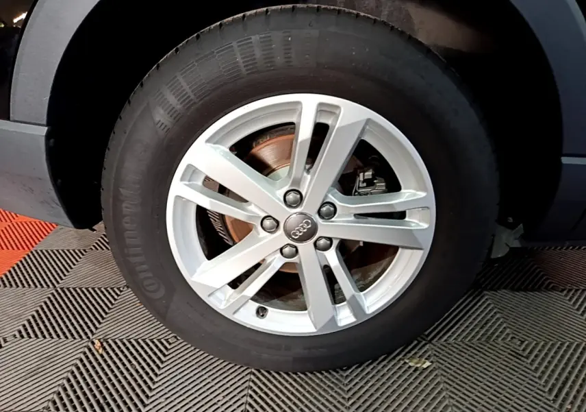 Gros plan sur la roue avant droite avec jante argentée de l'Audi Q3 noir 35 TDI 150 S Tronic Business Line.