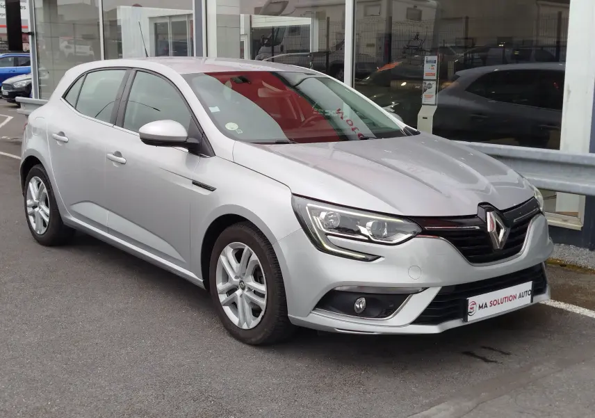 Renault Mégane gris titanium vue 3/4 avant droit, avec phares LED et jantes alliage visibles.