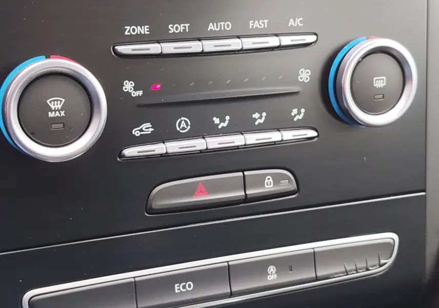 Détail du tableau de bord de la Renault Mégane 2018 gris Titanium, montrant les commandes de climatisation et les boutons de sécurité.