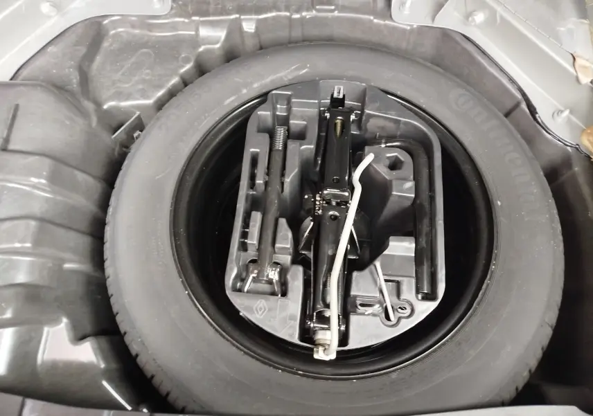 Vue rapprochée de la roue de secours et du kit d'outils dans le coffre d'une Renault Mégane gris titanium 2018.