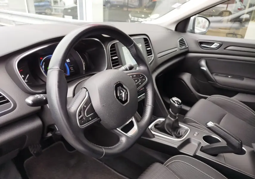 Intérieur de Renault Mégane 2018 vue côté conducteur, volant cuir, tableau de bord numérique et levier de vitesses manuel.