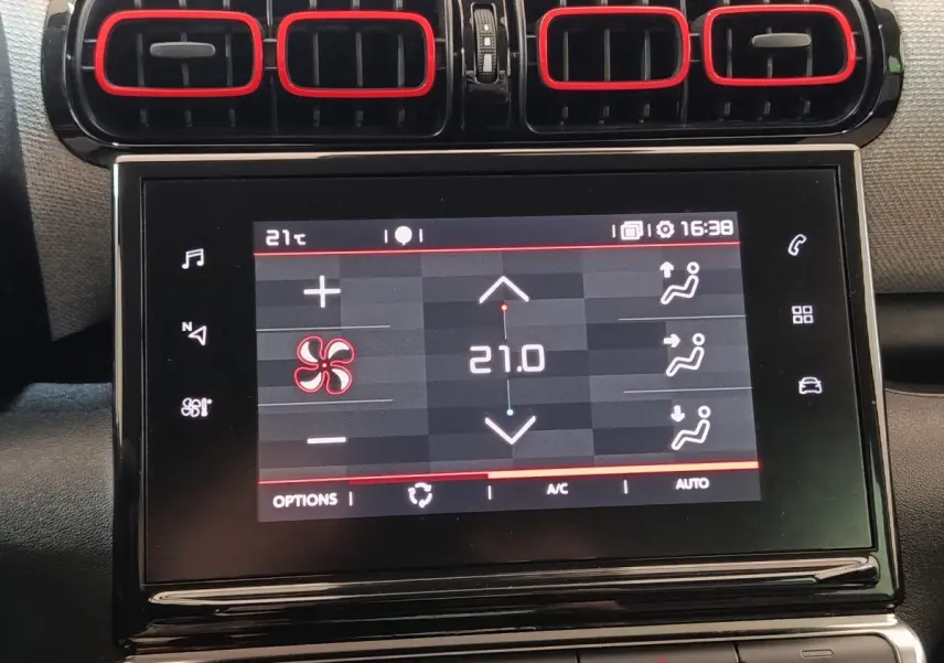 Écran tactile central affichant la climatisation à 21°C, entouré des aérateurs noirs avec contours rouges du Citroën C3 Aircross beige.