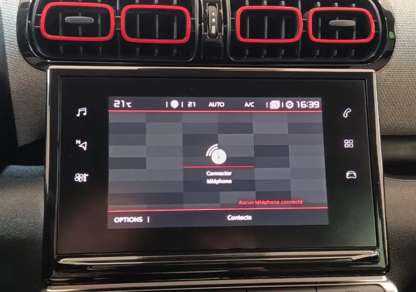 Vue rapprochée de l’écran tactile central et des aérateurs noirs avec contours rouges du tableau de bord beige du Citroën C3 Aircross.