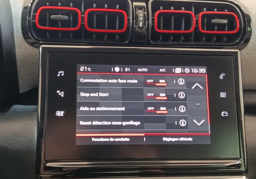 Gros plan sur l’écran tactile central et les aérateurs noirs avec contours rouges du tableau de bord beige du Citroën C3 Aircross.