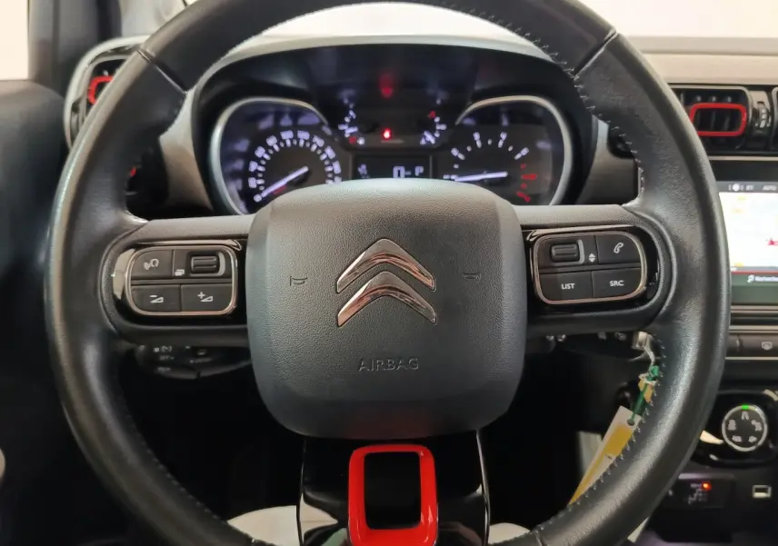 Vue rapprochée du volant noir avec logo Citroën et touches multifonctions rouges et noires du tableau de bord C3 Aircross.