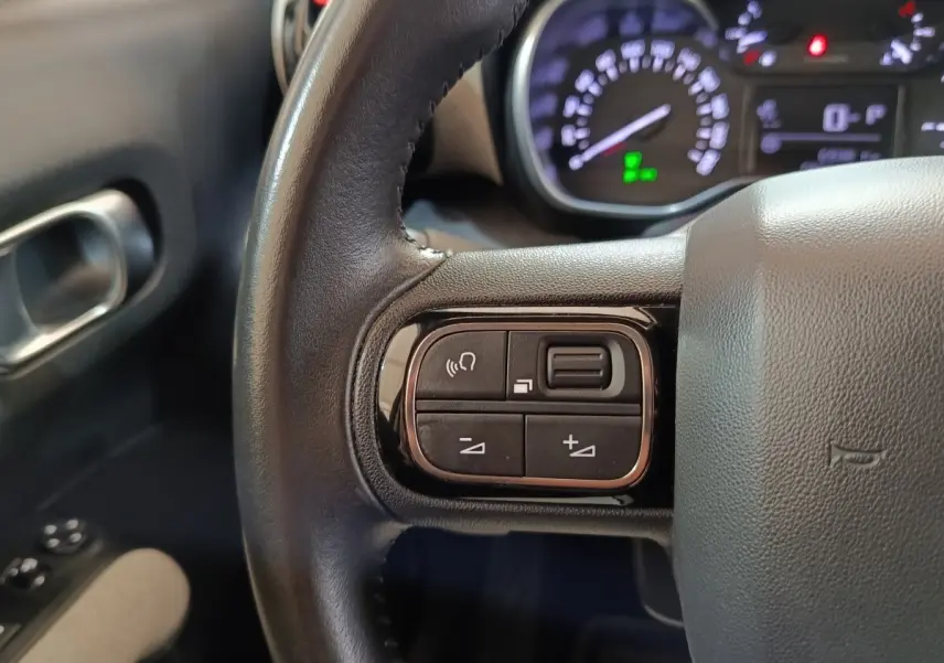 Gros plan sur le volant cuir noir de la Citroën C3 Aircross 2021 avec commandes audio intégrées côté gauche.