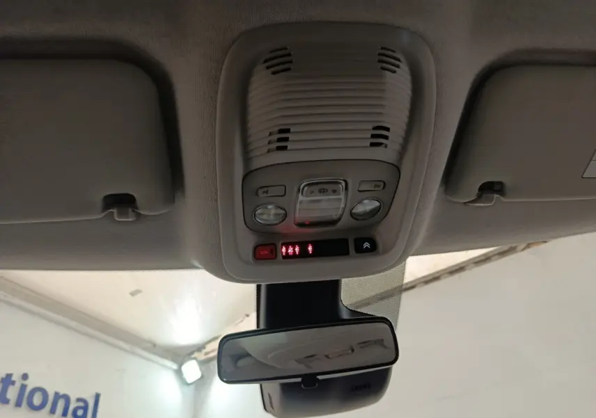 Vue intérieure du plafonnier et rétroviseur central d’un Citroën C3 Aircross beige, avec commandes d’éclairage et bouton SOS.