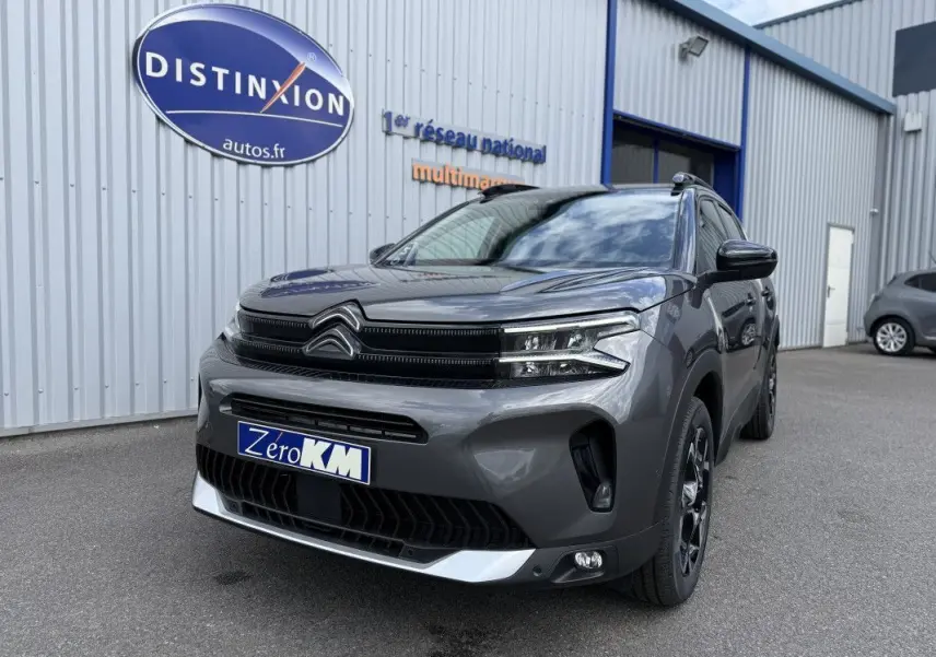 Vue 3/4 avant droit d'un Citroën C5 Aircross 2025 gris platinium métallisé avec calandre noire et jantes noires.