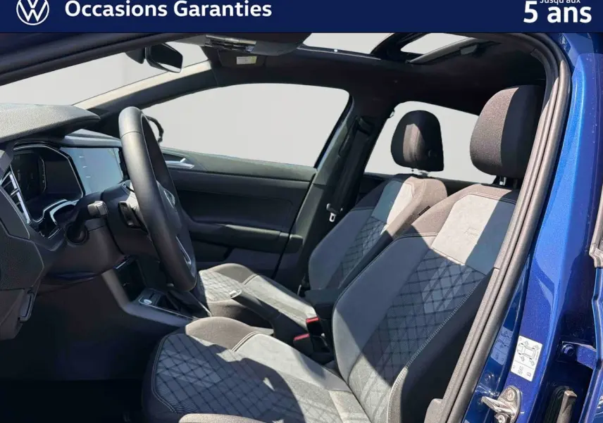 Vue intérieure côté conducteur du Volkswagen Taigo bleu 2025, sièges sport confort en tissu gris et noir.