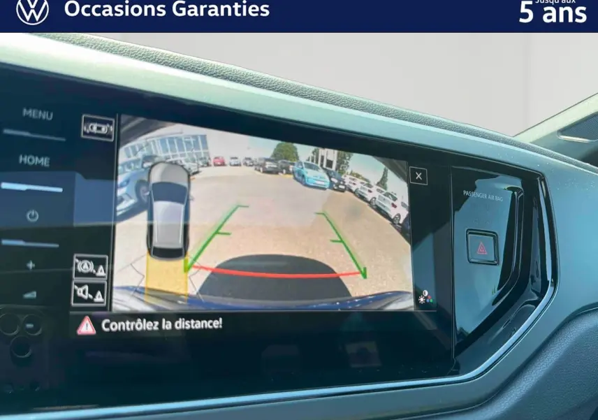 Écran tactile intérieur montrant la caméra de recul du Volkswagen Taigo bleu, avec aides au stationnement visibles.