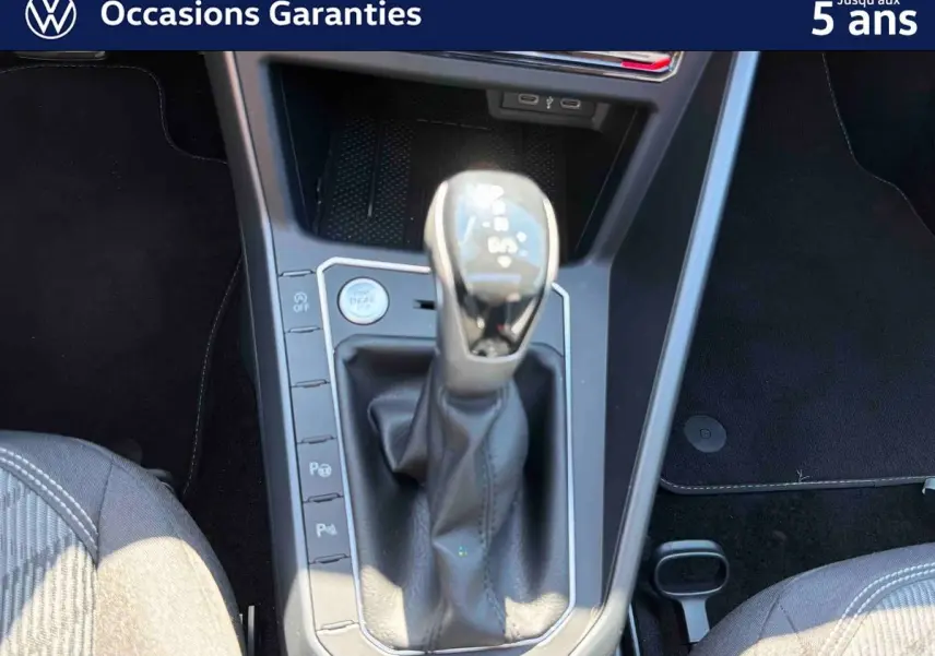 Gros plan sur la console centrale du Volkswagen Taigo bleu, mettant en valeur le levier de vitesse manuel et les commandes de stationnement.
