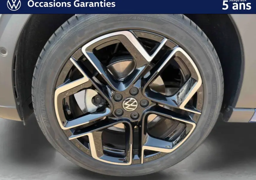 Gros plan sur la jante alliage noir et argent 18 pouces du Volkswagen Taigo bleu, avec logo VW au centre.