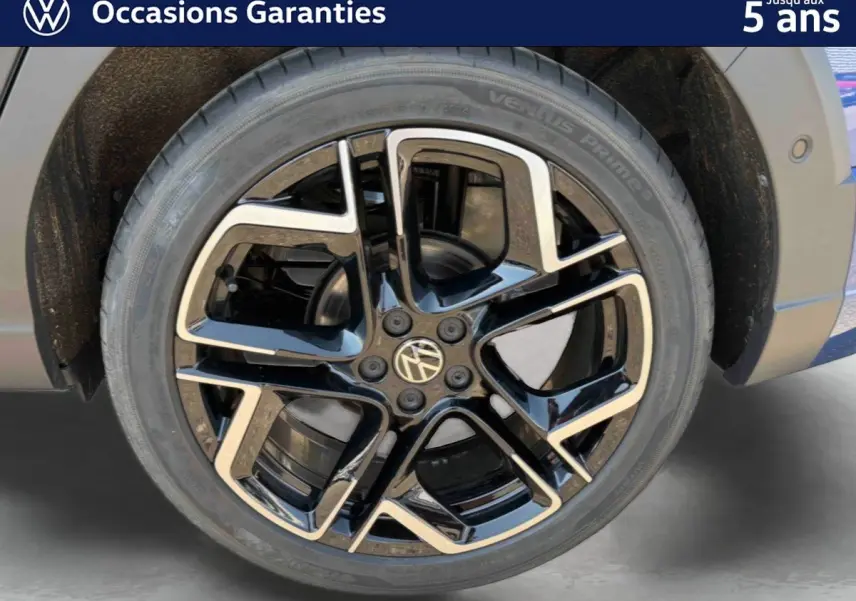 Gros plan sur la jante noire et argentée 18 pouces du Volkswagen Taigo bleu, avec logo VW au centre.