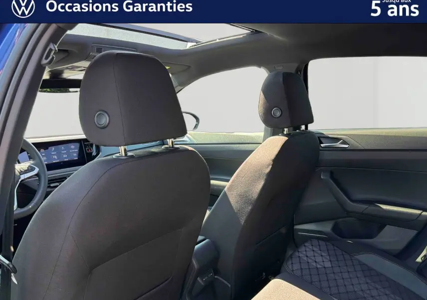 Vue intérieure arrière du Volkswagen Taigo bleu 2025 avec toit ouvrant électrique et sièges tissu noirs.