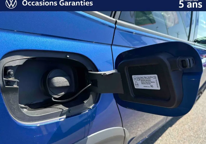 Détail de la trappe à carburant ouverte côté droit sur Volkswagen Taigo 2025 bleu métallisé.