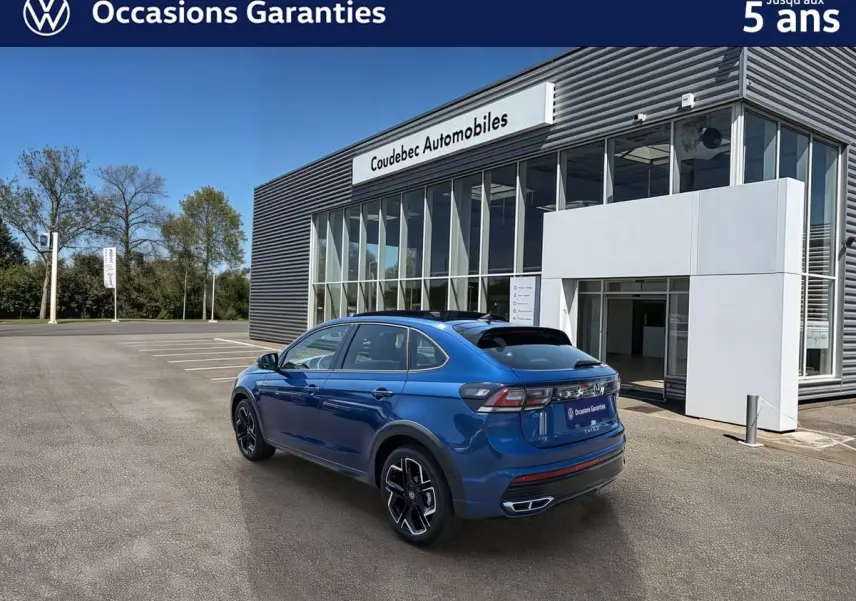 Volkswagen Taigo bleu métallisé vu en 3/4 arrière droit, avec jantes alliage noires et toit ouvrant en verre.
