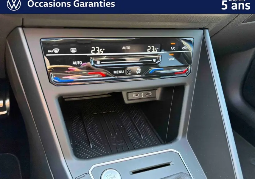 Gros plan sur la console centrale noire du Volkswagen Taigo 2025, avec commandes climatisation tactile et bouton start/stop.