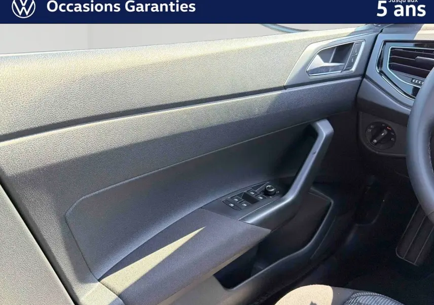 Détail de la porte avant gauche du Volkswagen Taigo bleu 2025, avec commandes des vitres et poignée intégrée.