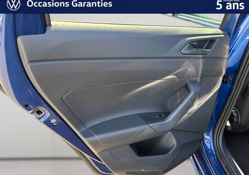 Vue rapprochée de la porte arrière gauche bleu métallisé du Volkswagen Taigo, montrant la garniture intérieure noire.