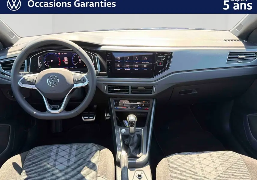 Vue intérieure avant du Volkswagen Taigo 2025 avec volant multifonctions, écran tactile et levier de vitesse manuel.