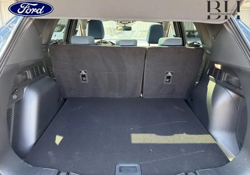 Coffre spacieux vu de l'arrière avec banquette arrière relevée d'un Ford Kuga bleu, intérieur noir.