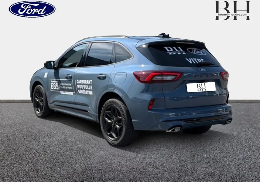 Vue 3/4 arrière droite d'un Ford Kuga bleu métallisé avec jantes noires et marquages publicitaires sur les portes.