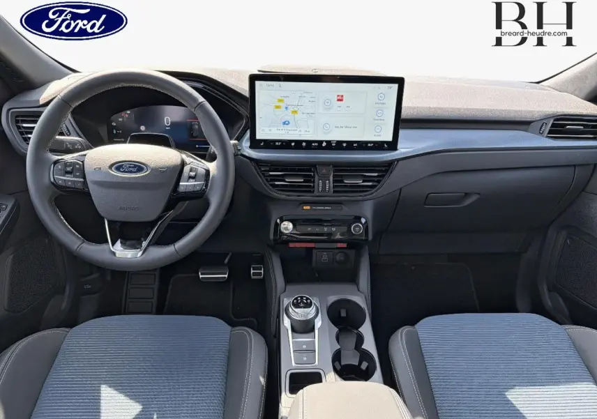 Vue intérieure frontale du Ford Kuga 2026 montrant le volant multifonction, écran tactile central et sièges tissu bleu et cuir noir.