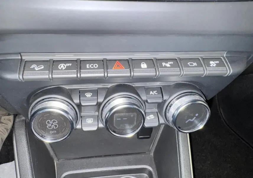 Gros plan sur la console centrale du Dacia Duster 2020, montrant les commandes de climatisation et les boutons de fonction.