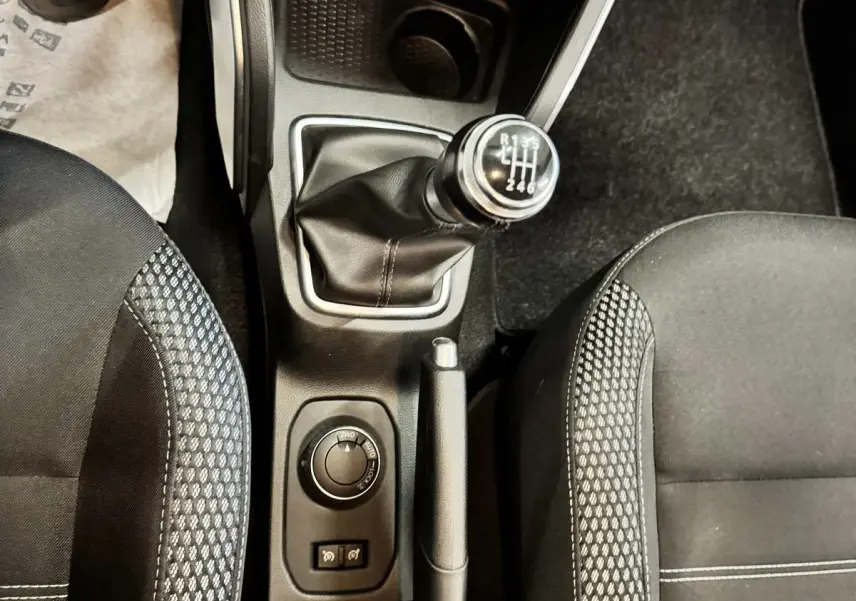 Vue plongeante sur la console centrale du Dacia Duster 2020, montrant levier de vitesse manuel et sièges noirs à motifs.