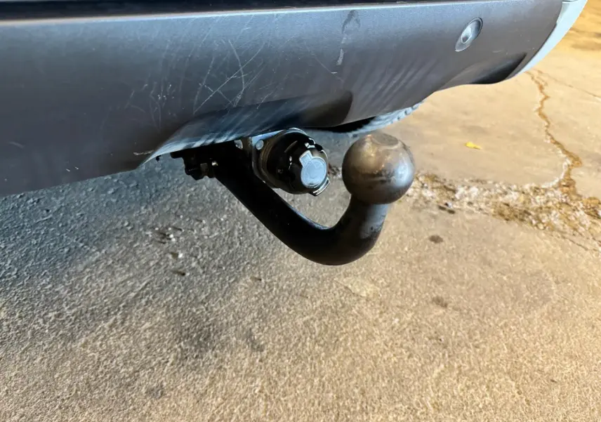 Gros plan sur l'attelage noir fixé sous le pare-chocs arrière gris du Dacia Duster 2020.