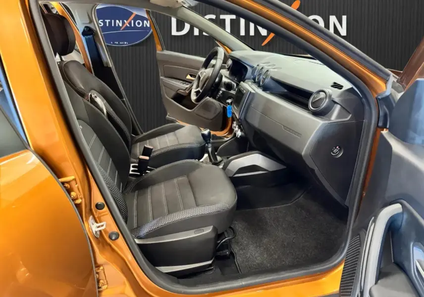 Vue intérieure côté conducteur du Dacia Duster orange 2020, sièges noirs et tableau de bord moderne.