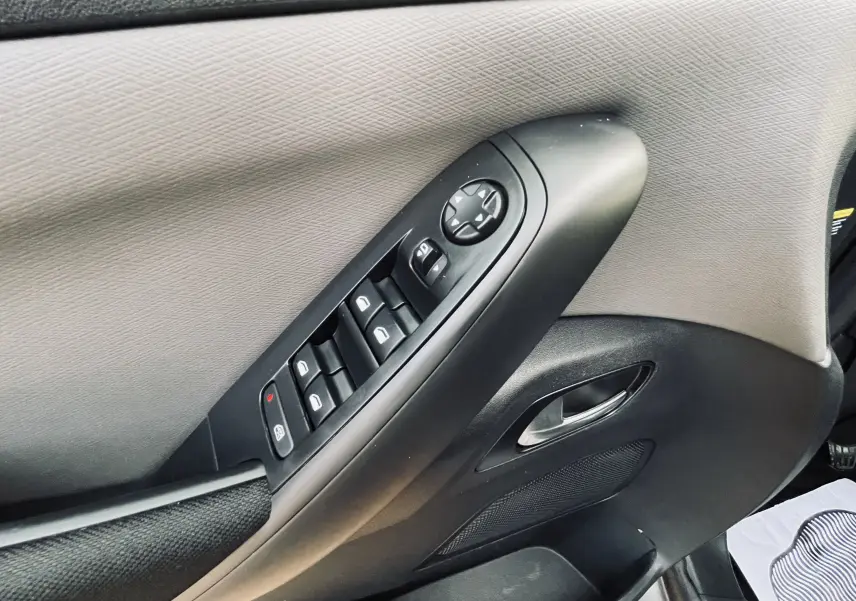 Panneau de porte côté gauche du Citroën C4 Picasso gris, avec commandes électriques des vitres et rétroviseurs.