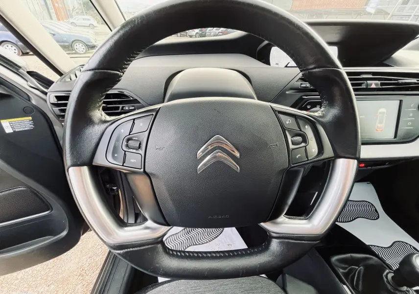 Vue rapprochée du volant cuir noir avec commandes intégrées du tableau de bord d'une Citroën C4 Picasso gris métal 2018.