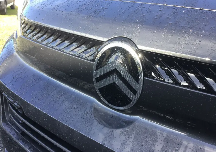 Gros plan sur la calandre et le logo Citroën d'un Jumpy XL gris titane couvert de gouttes d'eau.