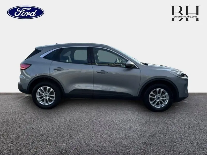 Profil droit du Ford Kuga 2023 gris Solar métallisé avec jantes alu et barres de toit visibles.