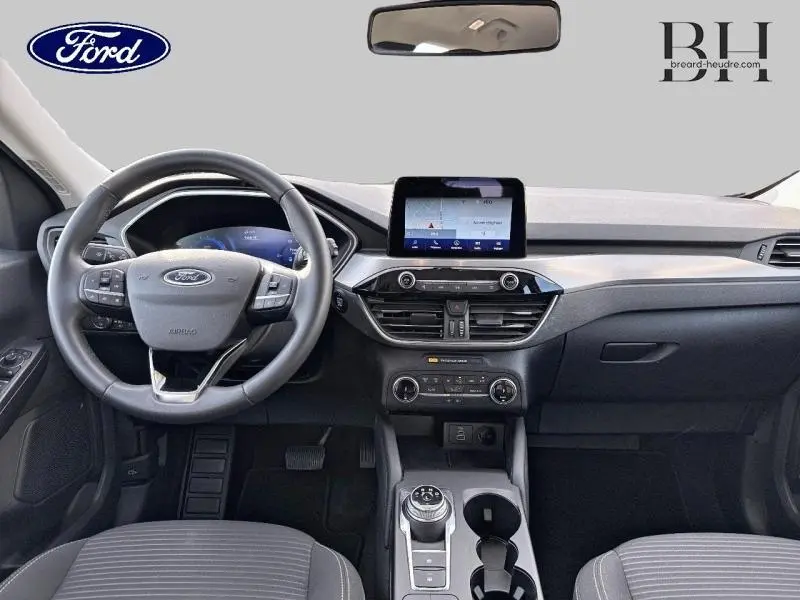 Intérieur du Ford Kuga 2023 avec tableau de bord moderne, volant cuir multifonction et écran tactile central.