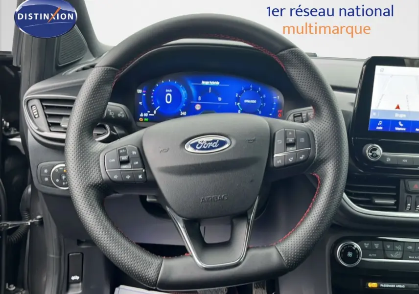 Vue intérieure centrée sur le volant perforé avec surpiqûres rouges et tableau de bord numérique du Ford Puma gris Magnetic Metal.