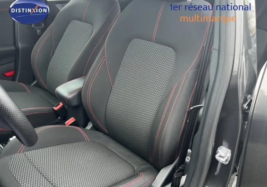 Gros plan sur les sièges avant en tissu noir avec surpiqûres rouges du Ford Puma gris Magnetic Metal, porte ouverte côté droit.