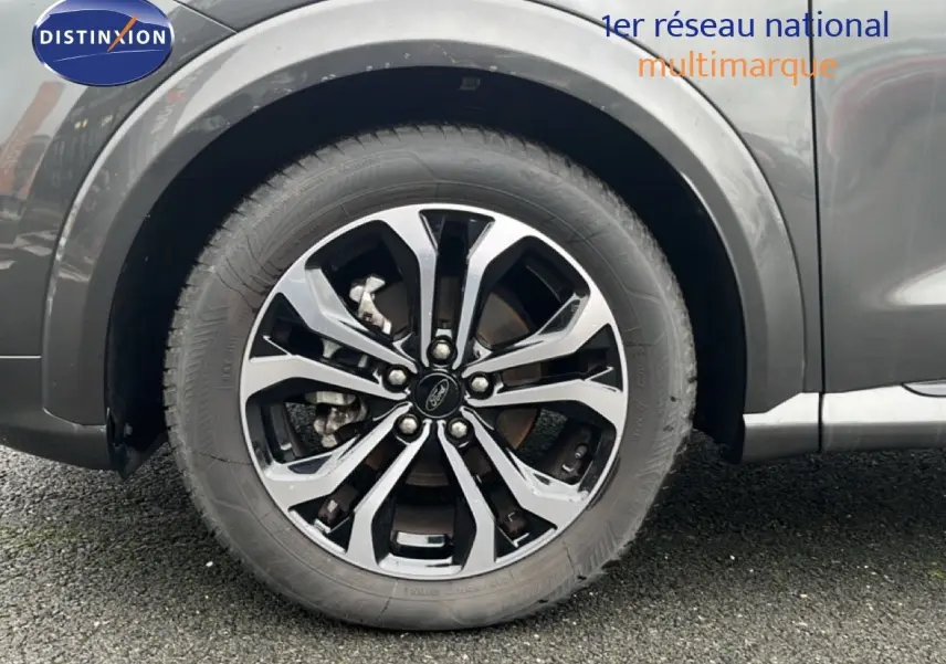 Gros plan sur la roue avant droite avec jante alliage bicolore du Ford Puma gris Magnetic Metal.