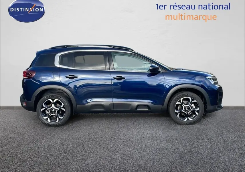 Profil latéral droit d'un Citroën C5 Aircross 2025 bleu eclipse métal avec jantes alliage bicolores et protections noires.