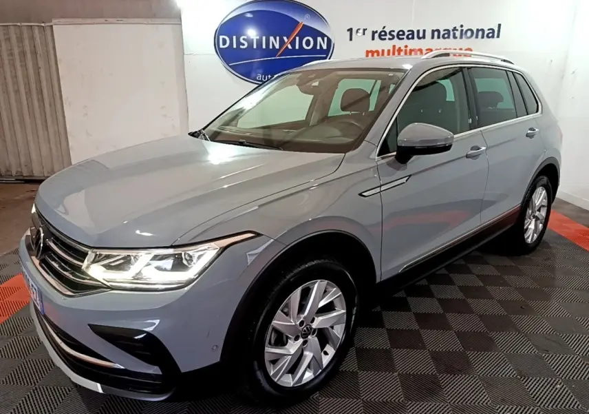 Volkswagen Tiguan gris foncé vu en 3/4 avant droit dans un showroom avec éclairage intérieur.