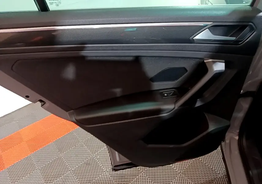 Porte arrière droite ouverte du Volkswagen Tiguan gris foncé, avec garniture intérieure noire et poignée intégrée.