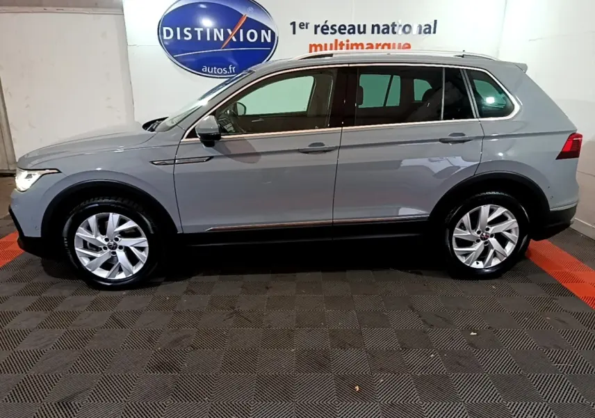 Vue latérale gauche d'un Volkswagen Tiguan gris foncé 2021 stationné en intérieur avec jantes alliage visibles.